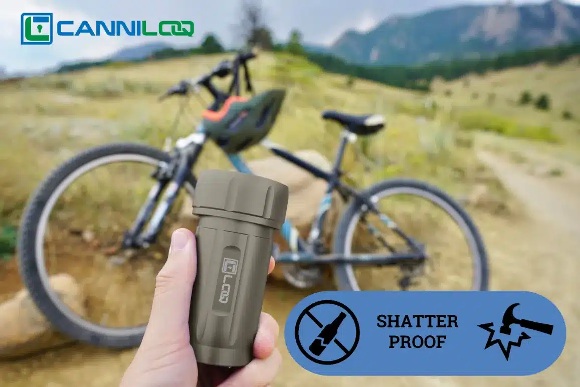 a gray canniloq shatter proof and smell proof container shown on a mountain bike trail