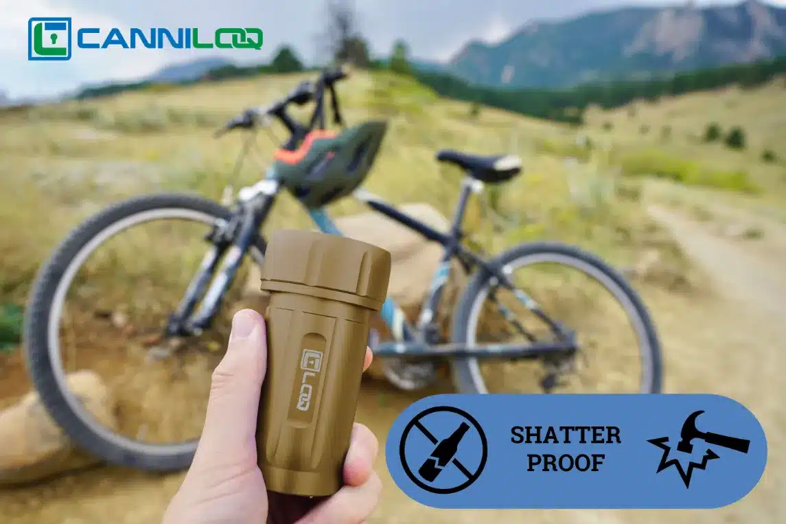 a tan canniloq shatter proof and smell proof container shown on a mountain bike trail