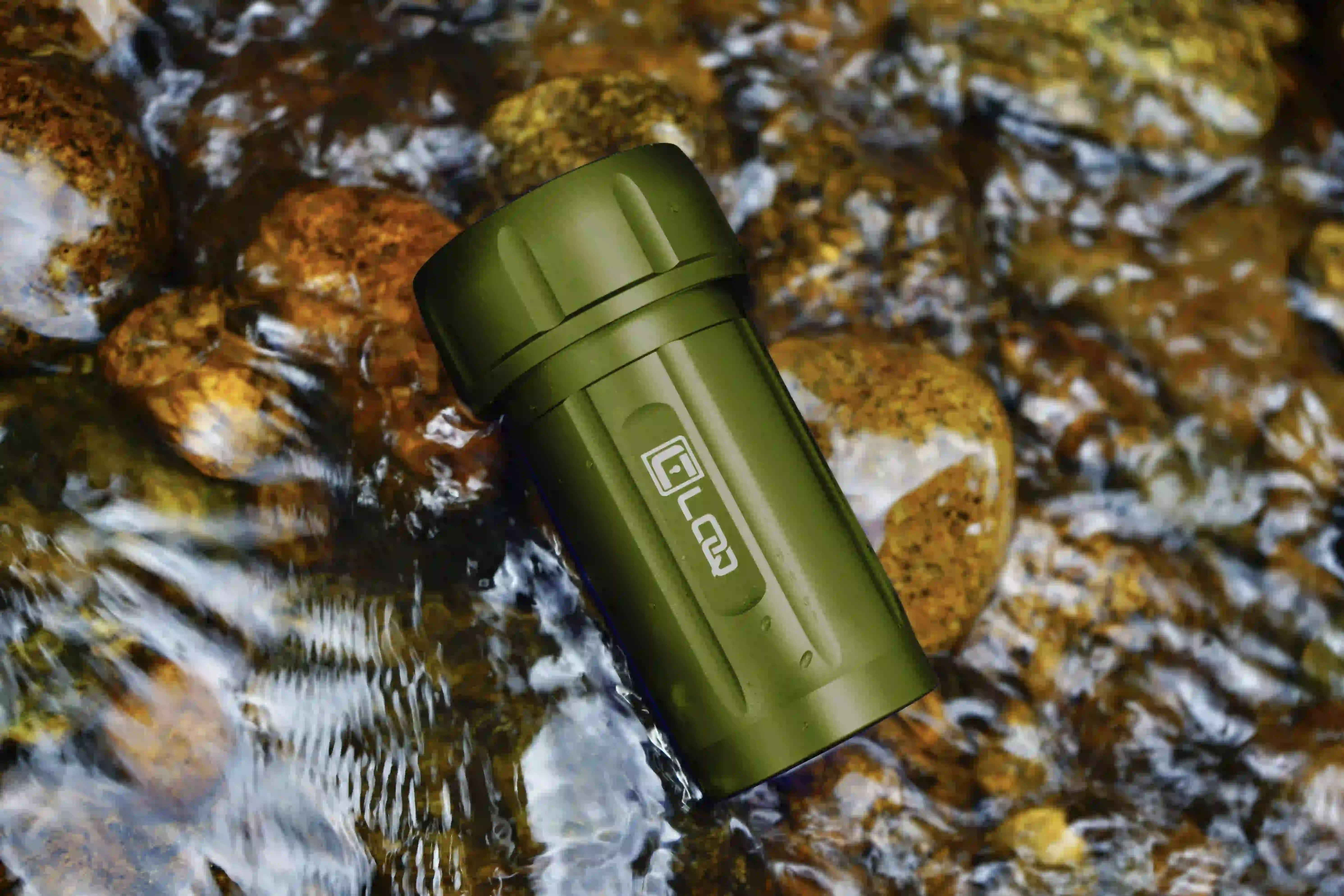 waterproof-canniloq-container-green a green waterproof smell proof canniloq container immersed in a flowing river